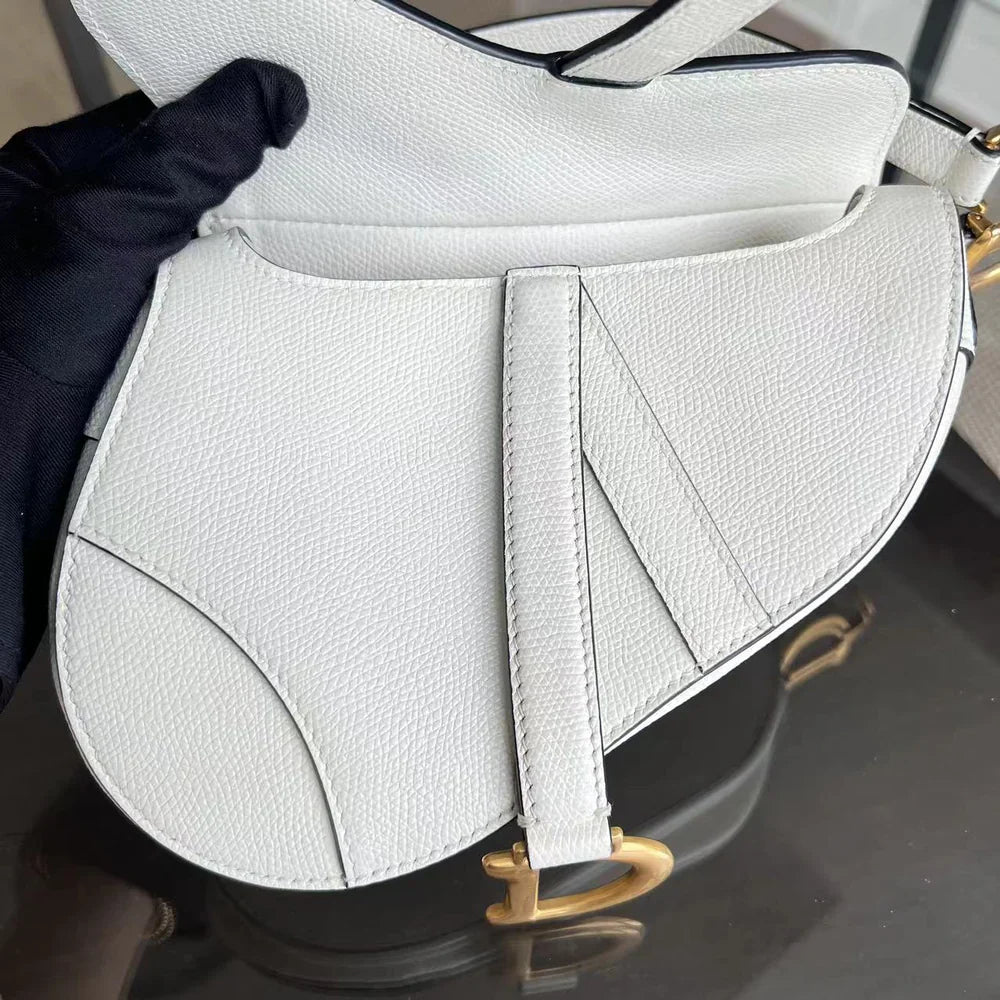 Kovancy Saddle Small 21 cm en cuir caviar blanc avec bandoulière et finitions dorées.