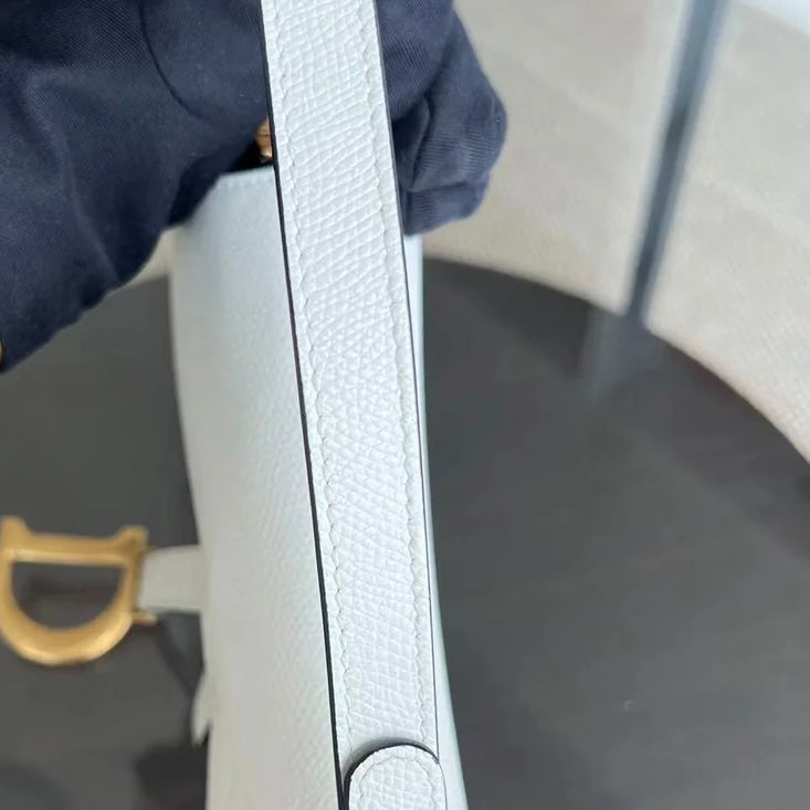Kovancy Saddle Small 21 cm en cuir caviar blanc avec bandoulière et finitions dorées.