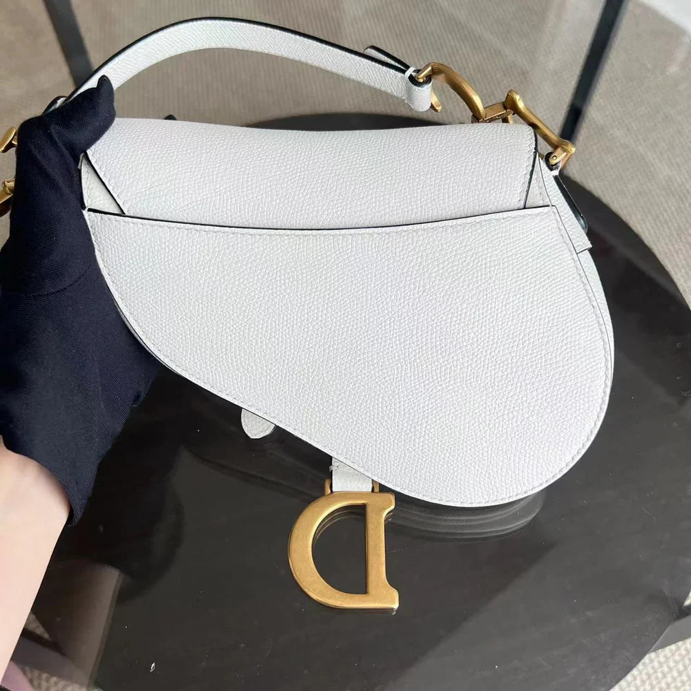 Kovancy Saddle Small 21 cm en cuir caviar blanc avec bandoulière et finitions dorées.