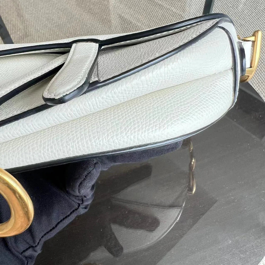 Kovancy Saddle Small 21 cm en cuir caviar blanc avec bandoulière et finitions dorées.