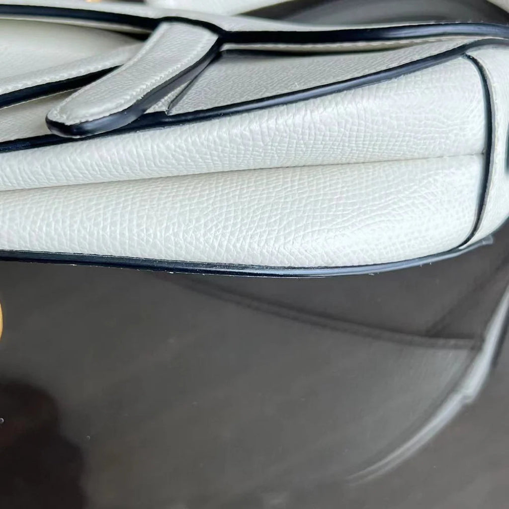 Kovancy Saddle Small 21 cm en cuir caviar blanc avec bandoulière et finitions dorées.